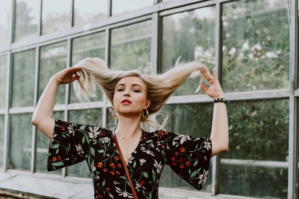 woman fluffing hair against window